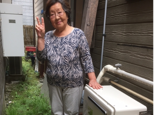 給湯器のそばでピースするお客さま