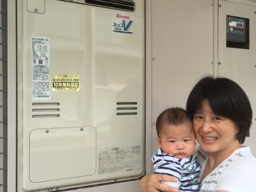 給湯器のそばでお子さまと笑顔を向けるお客さま