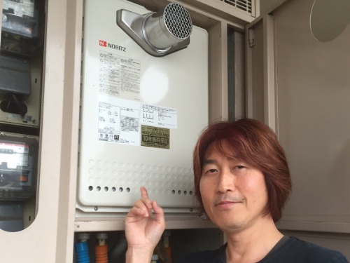 給湯器を指さして微笑むお客さま