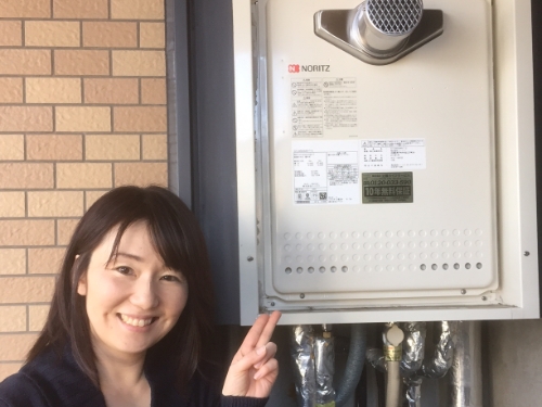 給湯器を指さしてにっこりするお客さま