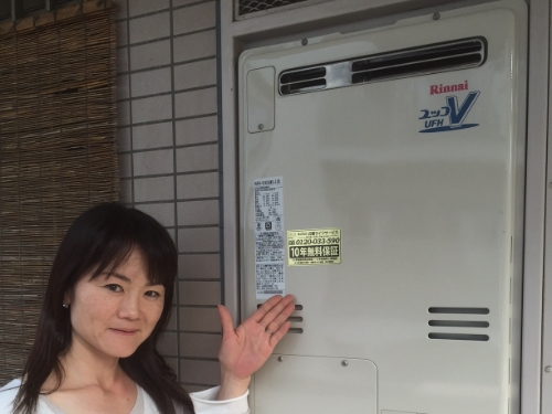 給湯器に手を向けてほほえむお客さま